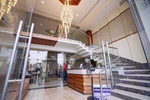 Una hall moderna con una scalinata in vetro, una reception e un lampadario.