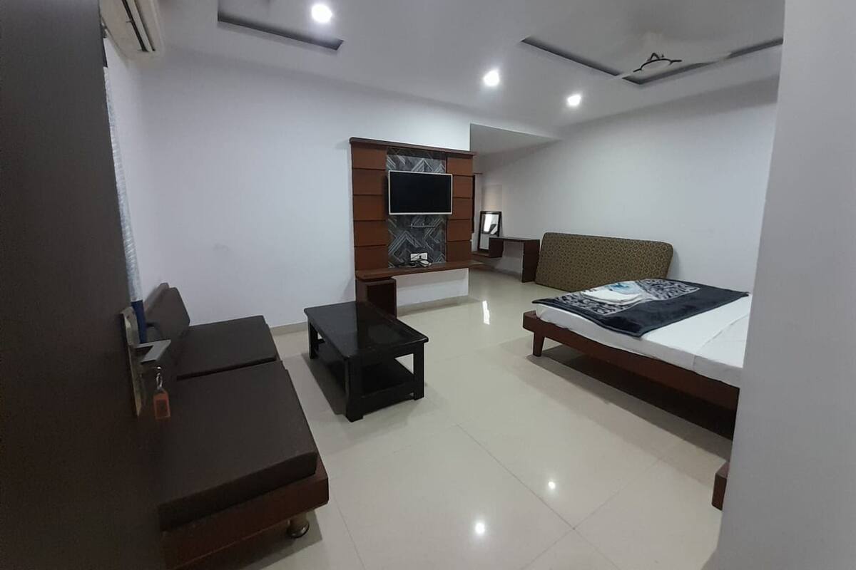 A modern hotel room with a bed, a desk, a TV mounted on a wall, and a ceiling fan.