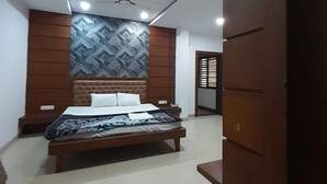 A bedroom with a bed, a wardrobe, and a ceiling fan. - Hotel Mezbaan  (Raipur)