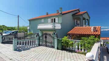 A two-story building with a tiled roof, a gated entrance, and a paved driveway.