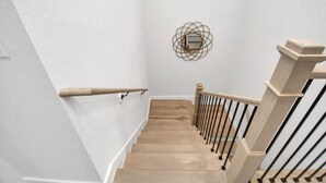 Una scala con gradini in legno, ringhiere nere, pareti bianche e un elemento decorativo a parete.