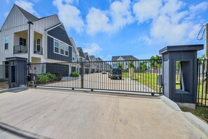 Un lotissement résidentiel sécurisé, avec des maisons modernes, un ciel dégagé et une allée pavée.