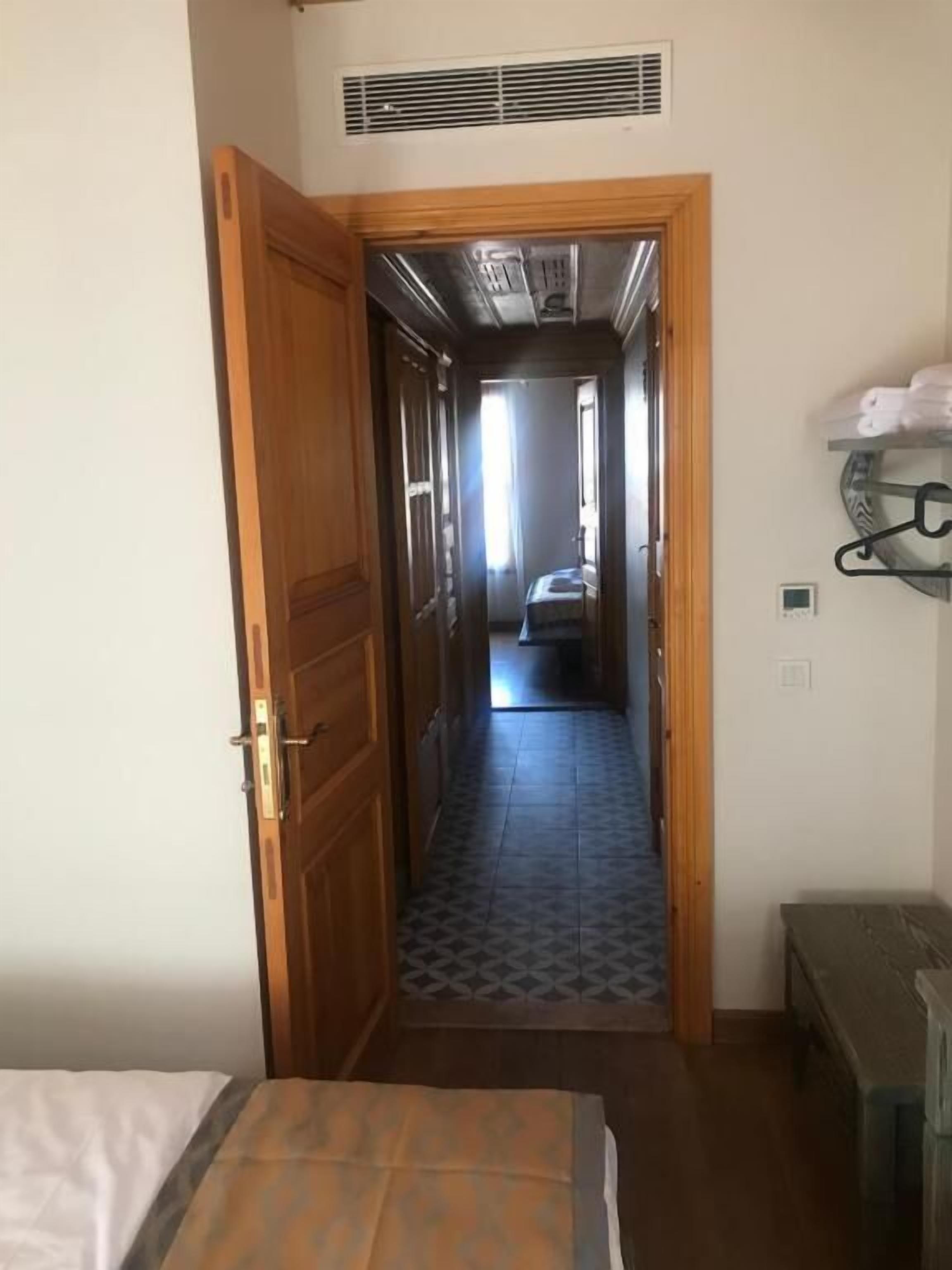 Un pasillo estrecho que conduce a un dormitorio con una cama y una pequeña mesa.