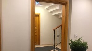 A hallway leading to a staircase with a wooden door and a potted plant. - Green Mansion (Istanbul)