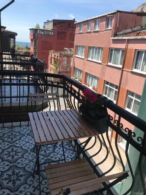 Een balkon met een patroonvloer, een houten tafel en een metalen hekwerk.