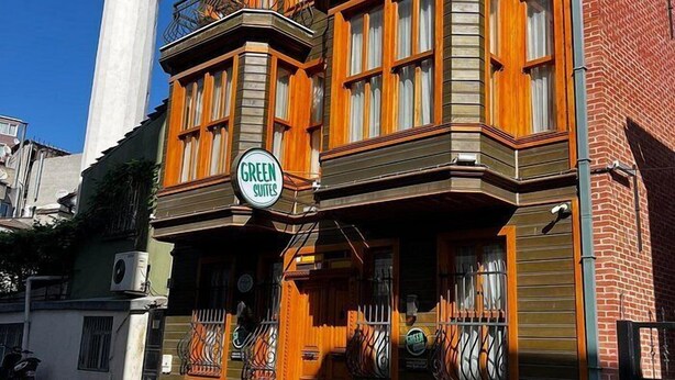 A building with a sign reading "GREEN SUITES" and a white tower in the background. - Green Mansion (Istanbul)