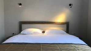 A neatly made bed with a patterned bedspread, a wooden headboard, and two wall-mounted light fixtures. - Green Mansion (Istanbul)