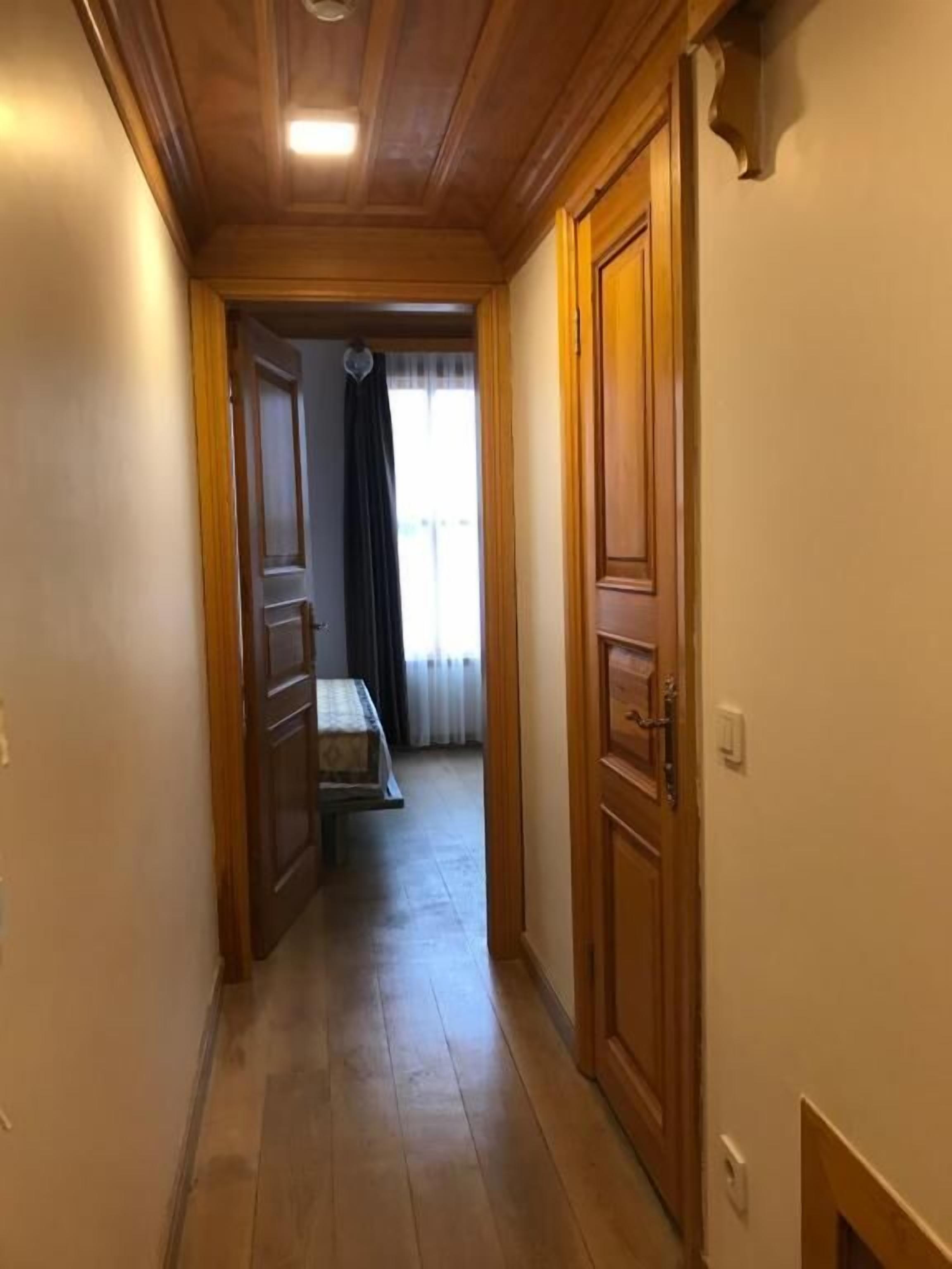 A narrow hallway with wooden doors and a bench in the background.