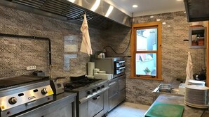A commercial kitchen with stainless steel appliances, a window, and patterned walls. - Green Mansion (Istanbul)