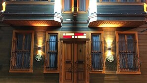 A building with a wooden facade, a central double door, and two lit signs on either side. - Green Mansion (Istanbul)