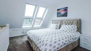A bedroom with a bed, a window, a radiator, and a nightstand. - 3br-walktocitycentre-garden-freeparking (Salford)