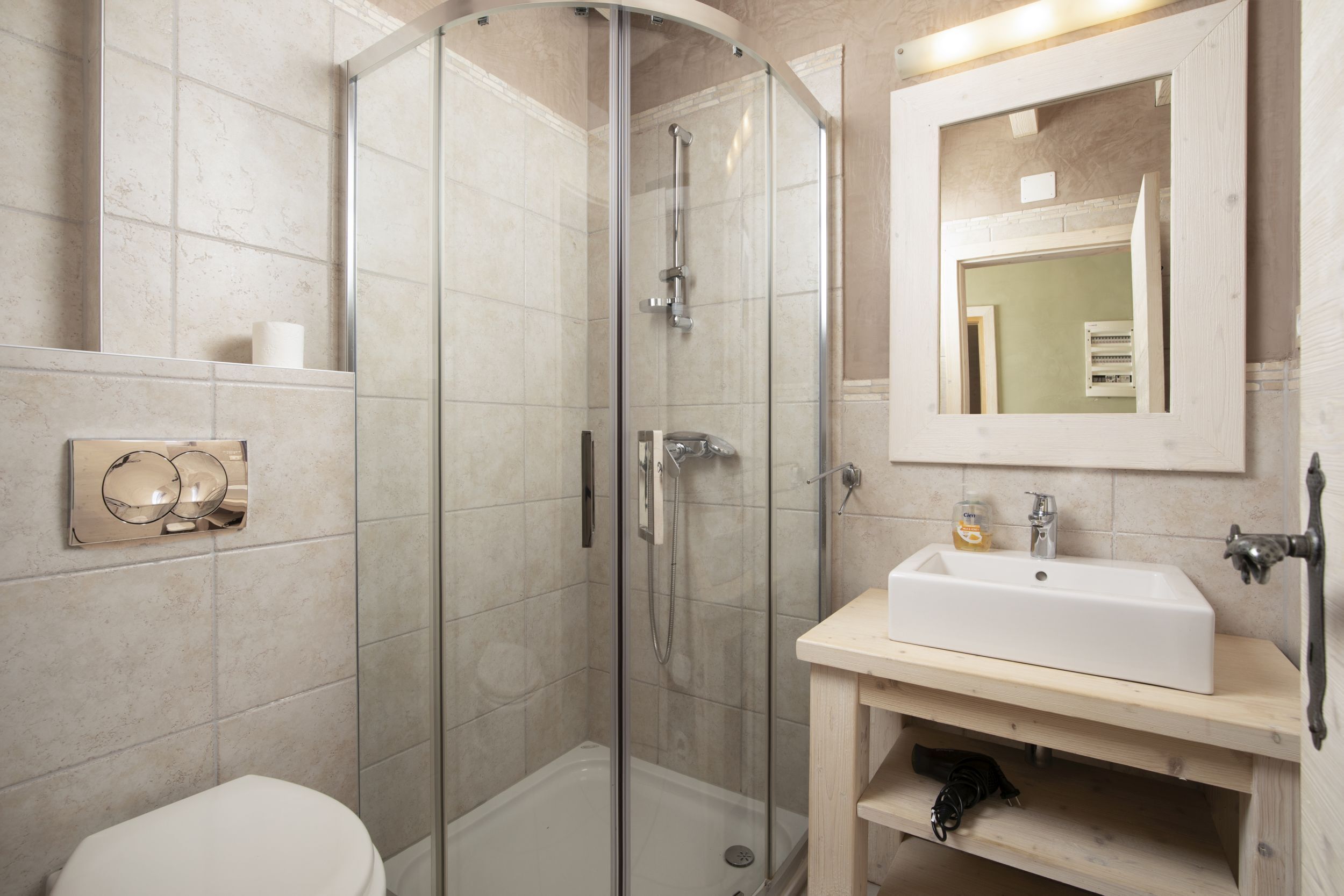 A modern bathroom with a glass-enclosed shower, a white sink, and a toilet.