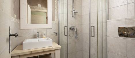 A modern bathroom with a glass-enclosed shower, a white sink, and a toilet.