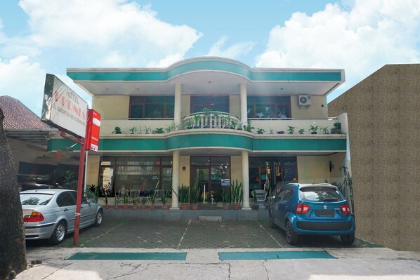 A two-story hotel with a balcony on the upper floor, potted plants in front, and a signboard. - Hotel O Kebon Jeruk Near Gedung Sate Formerly Kurnia Hotel (Bandung)