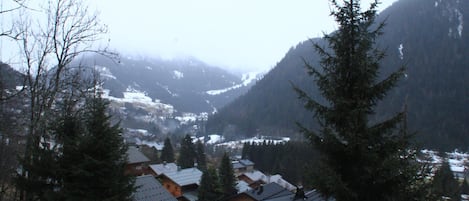 A mountainous village with snow-covered roofs and dense forest.