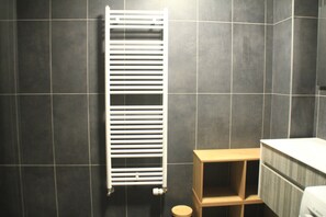 A bathroom with a white radiator, dark tiled walls, and a wooden bench. - Imperial Ip402 Cosy & View 4 Pers (Chatel)