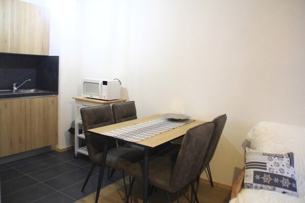 A compact kitchen with a microwave, a sink, and a dining area with a table and chairs.