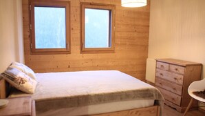 A wooden-paneled room with a bed, two windows, a dresser, and a chair. - Imperial Ip402 Cosy & View 4 Pers (Chatel)