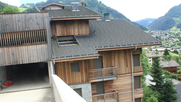 A multi-story wooden building with balconies and a view of a village in the background. - Imperial Ip402 Cosy & View 4 Pers (Chatel)
