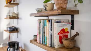 A kitchen shelf with cookbooks, a coffee maker, and a wooden mortar.