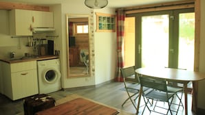Eine kompakte Küche mit Waschmaschine, einem Esstisch mit Stühlen und einem großen Fenster mit Vorhängen.