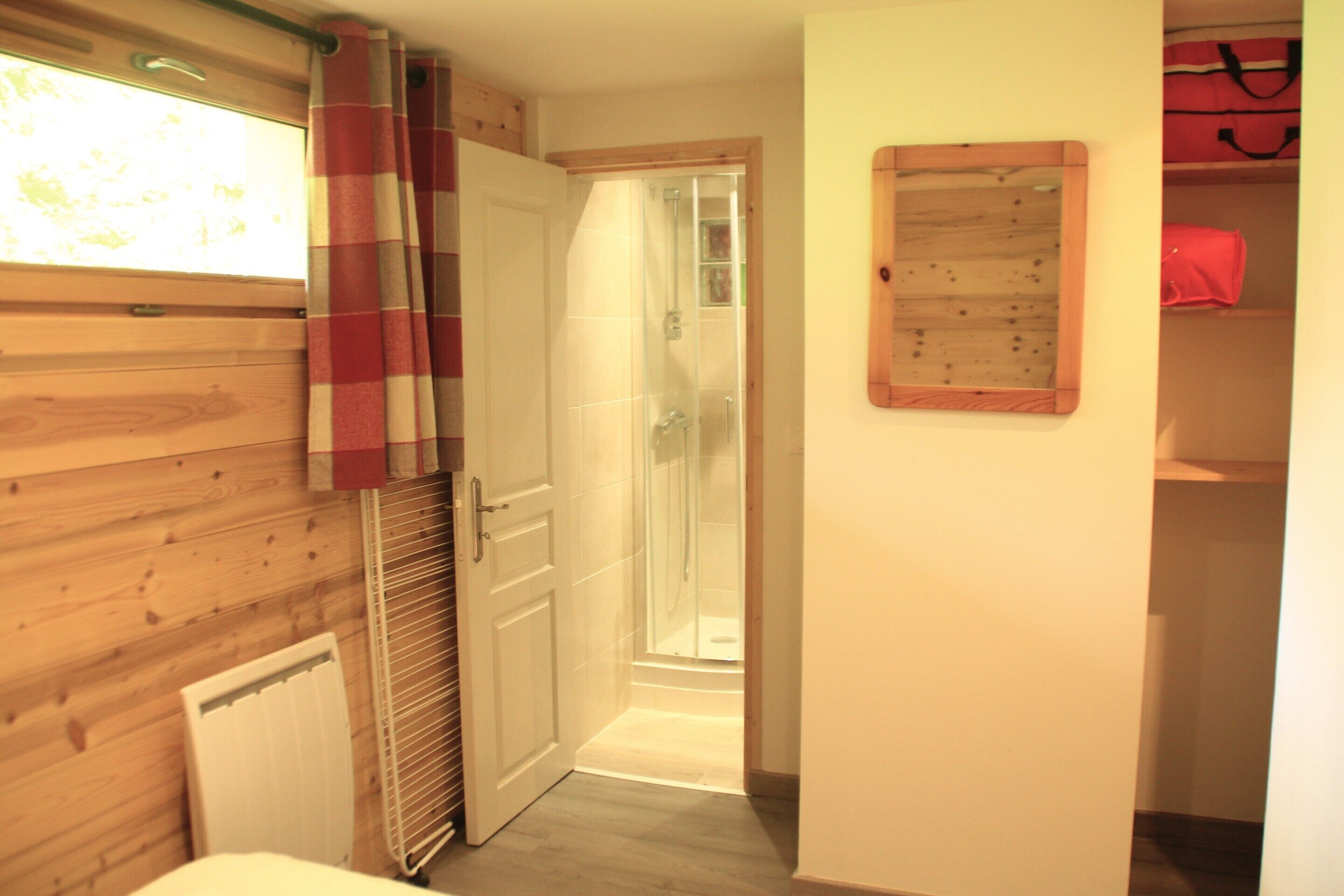 Une salle de bain avec des murs en bois, une douche, un radiateur et un miroir au mur.