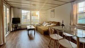 A spacious living area with a sofa, coffee table, and dining table with chairs. - Vakantiepark Klein Vink - 25 (Arcen)