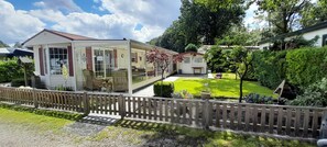 A two-story house with a covered patio, a fenced yard, and a well-maintained garden. - Vakantiepark Klein Vink - 25 (Arcen)