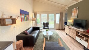 A modern living room with a black leather sofa, a small round table, and a television on a wooden cabinet. - Bungalowpark Simpelveld - Schakel 22 (Simpelveld)