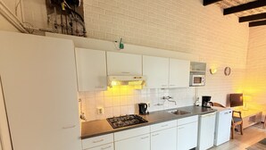 A modern kitchen with white cabinets, a gas stove, a sink, and a microwave.