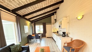 A cozy living room with a sofa, a coffee table, and a dining area with chairs and a table.