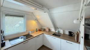 Una cocina compacta con ventana, un lavamanos, una estufa y una encimera.