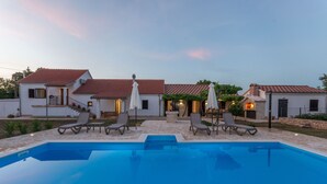 Un espace aménagé au bord de la piscine, avec une piscine à l’eau d’un bleu limpide, deux chaises longues et une petite table.