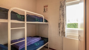 A dormitory room with bunk beds, a window with curtains, and a radiator. - Bungalowpark Simpelveld - Castra 40 (Simpelveld)