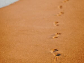 A close-up of a sandy surface with footprints leading into the distance.