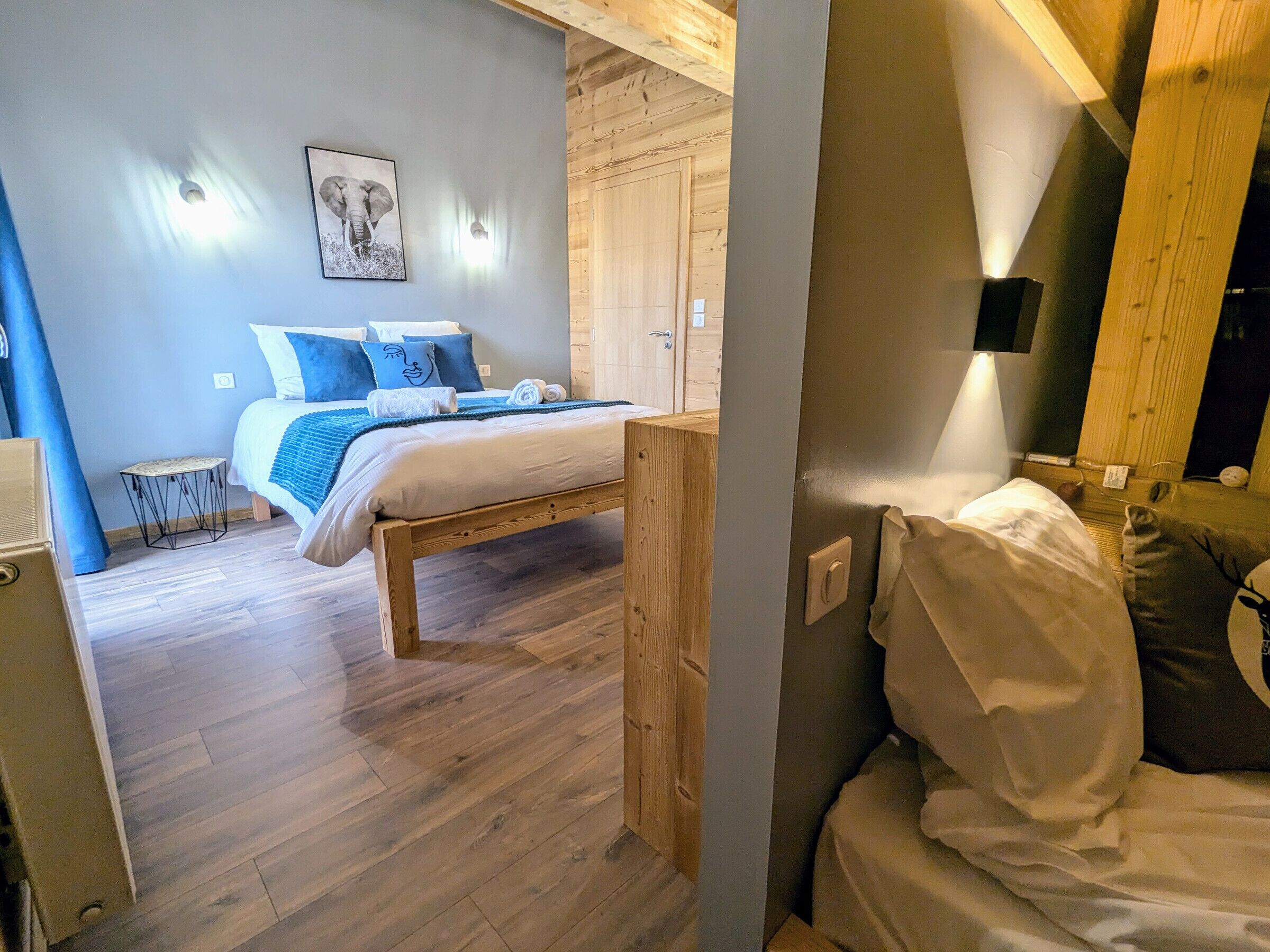 A bedroom with a wooden bed, a small bedside table, and a wall-mounted light.