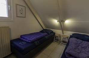 A small, compact room with a bed, a stool, and a radiator. - Bungalowpark Simpelveld - Alpha 64 (Simpelveld)