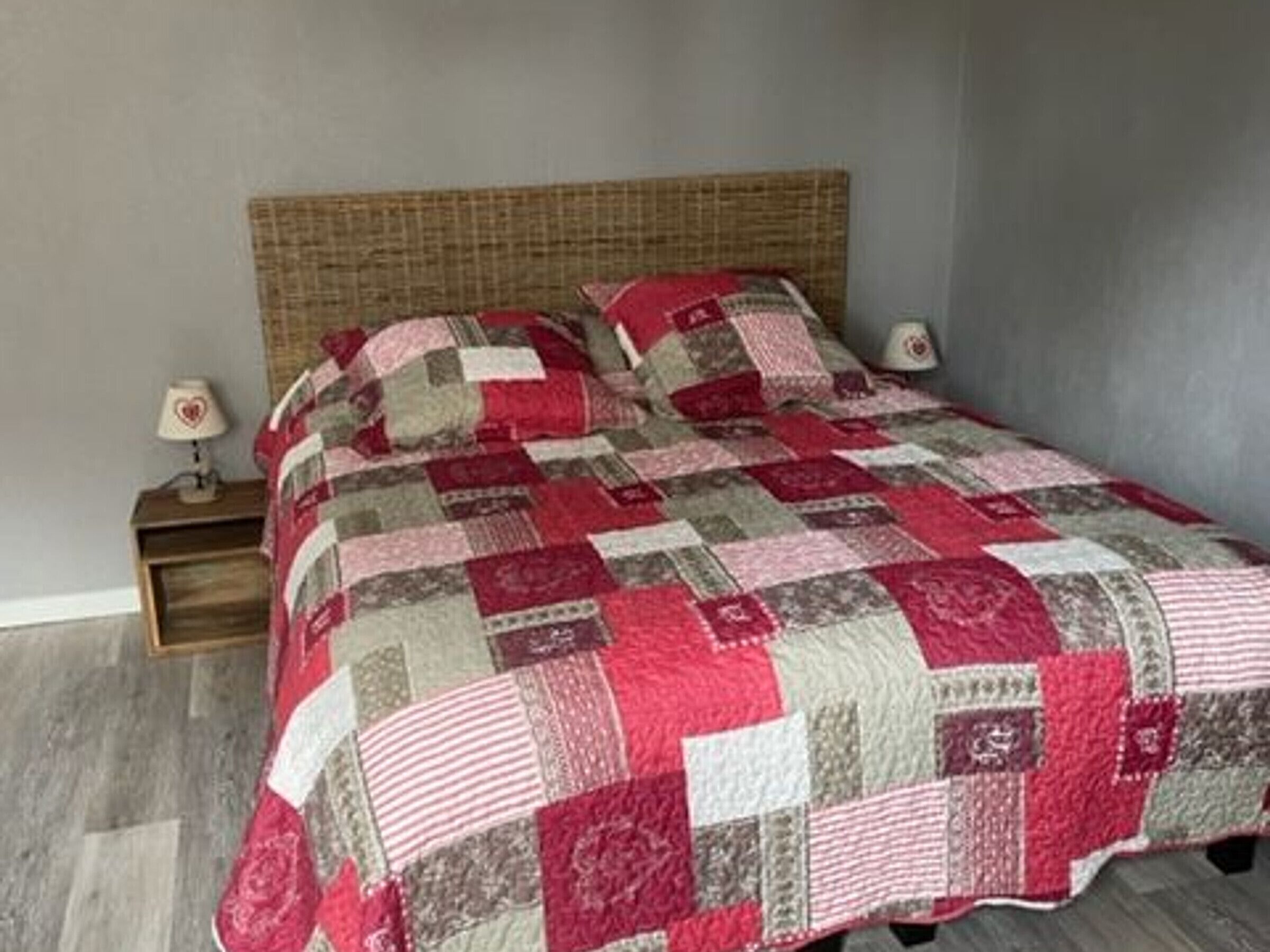 A bed with a checkered quilt, a wooden headboard, and two bedside tables with lamps.