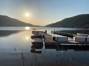A calm lake with boats docked at a wooden pier, surrounded by hills. - Spacious lodging in Gérardmer with lake view, 3 bedrooms, Wi-Fi and parking (Gérardmer)