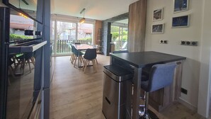 Une cuisine moderne avec un coin bar, un plancher en bois et un espace repas comprenant des chaises et une table.