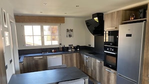Une cuisine moderne avec des meubles en bois, un four encastré et un réfrigérateur en acier inoxydable.