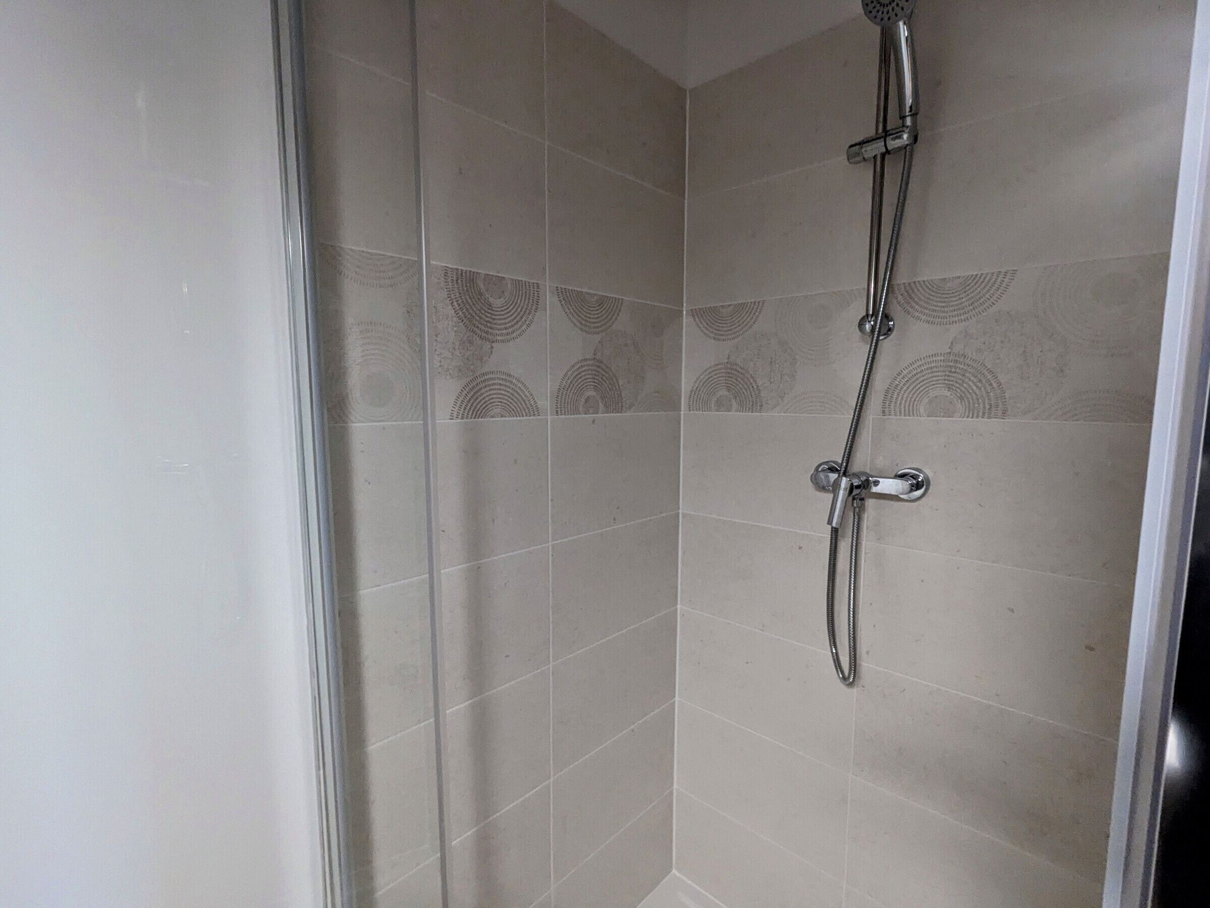 A shower with a handheld showerhead and a fixed wall-mounted showerhead.