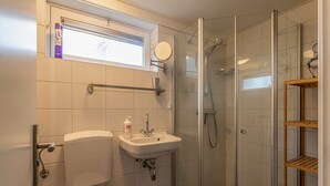 Un baño con inodoro, lavamanos y ducha con mampara de vidrio.
