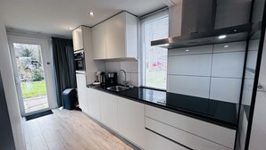 A modern kitchen with white cabinets, a black countertop, and a stainless steel range hood. - Bungalowpark Simpelveld - Delta 125 (Simpelveld)