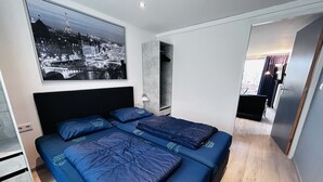 A modern hotel room with a large bed, a cityscape view, and a minimalist design. - Bungalowpark Simpelveld - Delta 125 (Simpelveld)