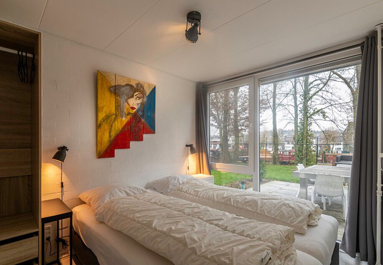 A bedroom with two beds, a painting on the wall, and a window with a view of the outdoors.
