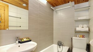 Ein modernes Badezimmer mit Waschbecken, Badewanne, Toilette und einem Regal mit Handtüchern.