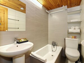 Ein modernes Badezimmer mit Waschbecken, Badewanne, Toilette und einem Regal mit Handtüchern.