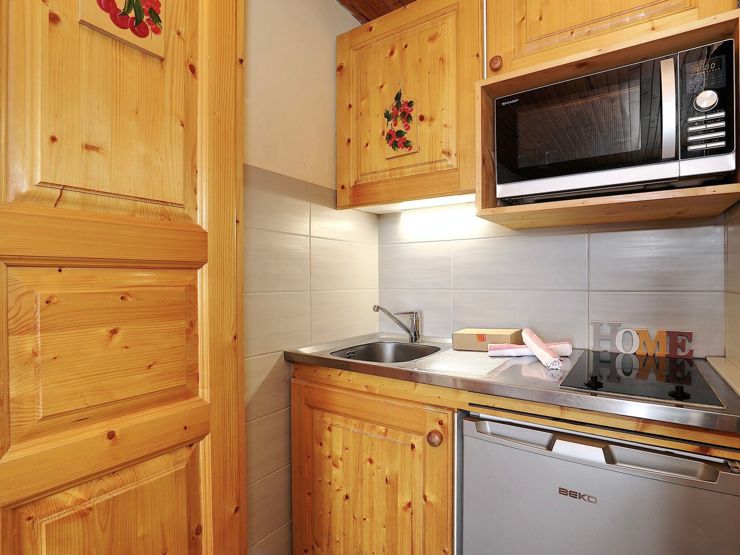 Una cocina con armarios de madera, un lavamanos de acero inoxidable, un microondas y un lavavajillas.