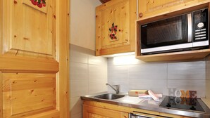 Eine Küche mit Holzschränken, einer Edelstahlspüle, einer Mikrowelle und einem Geschirrspüler.